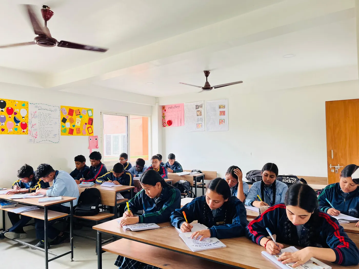 Maia Academy students writing and studying at their desks in a bright, quiet classroom